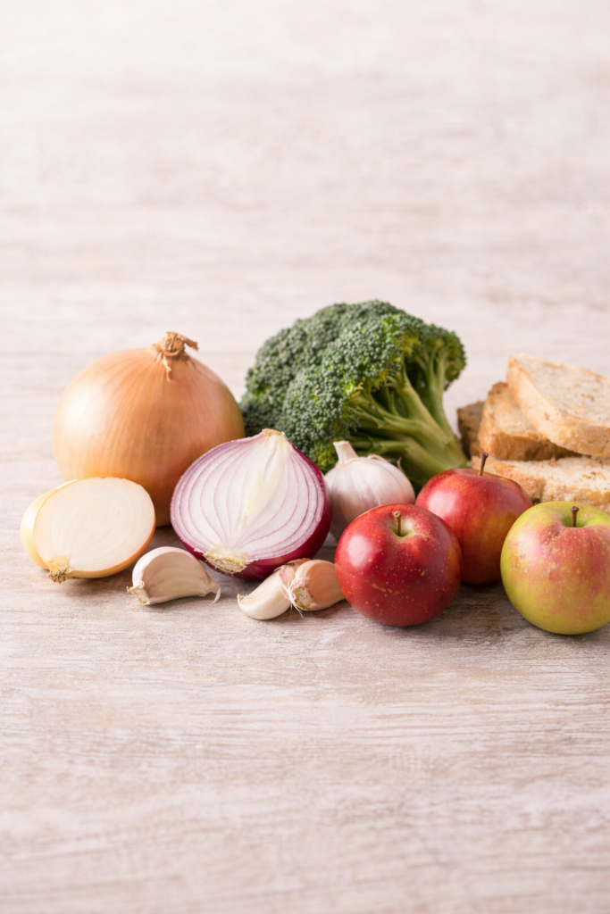 Magas FODMAP ételek – hagyma, fokhagyma, alma és kenyér –, amelyek IBS-nél gyakran puffadást és görcsöt okoznak.